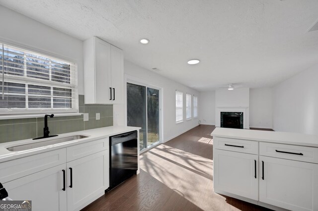 kitchen featuring sink, black dishwasher, a textured ceiling, decorative backsplash, and white cabinets