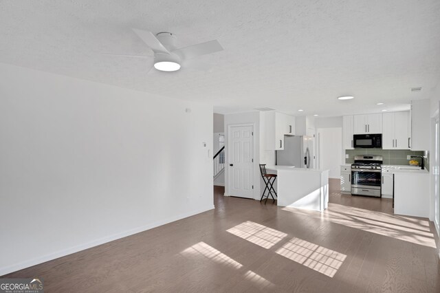 unfurnished living room with dark hardwood / wood-style flooring and ceiling fan