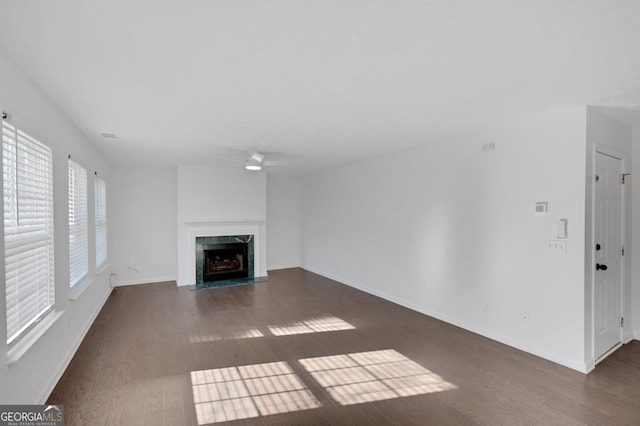 unfurnished living room featuring a high end fireplace, dark hardwood / wood-style flooring, and ceiling fan