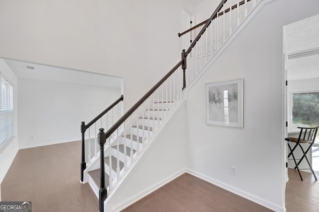 stairway featuring a towering ceiling and hardwood / wood-style flooring