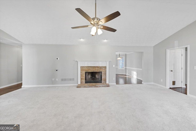 unfurnished living room with a fireplace, dark colored carpet, vaulted ceiling, and ceiling fan