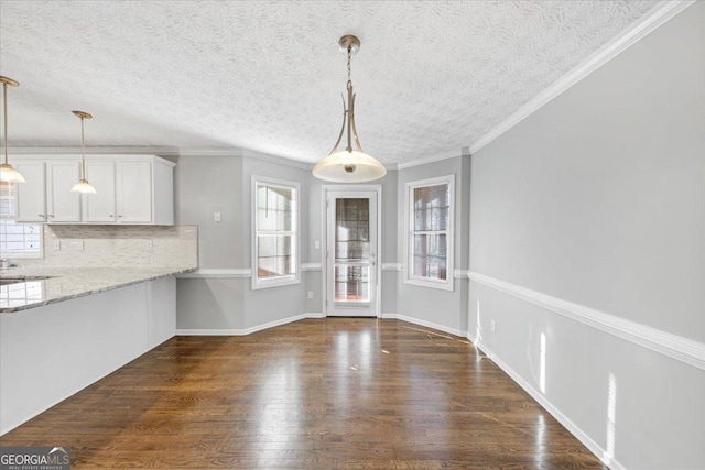 unfurnished dining area featuring a textured ceiling, dark hardwood / wood-style floors, and crown molding