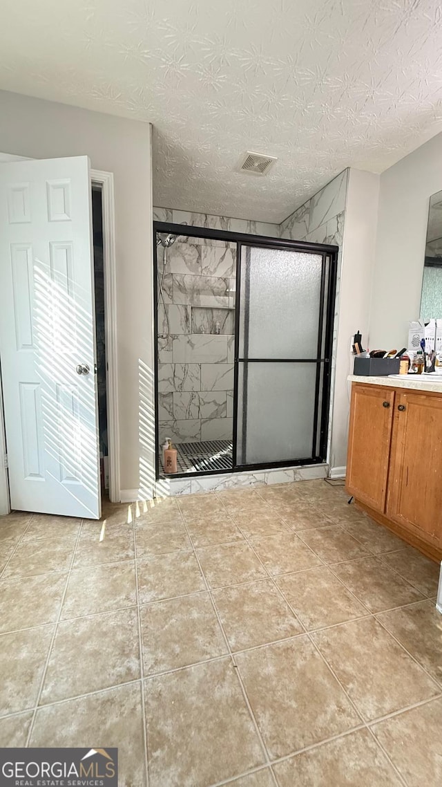 bathroom with tile patterned flooring, vanity, a textured ceiling, and an enclosed shower