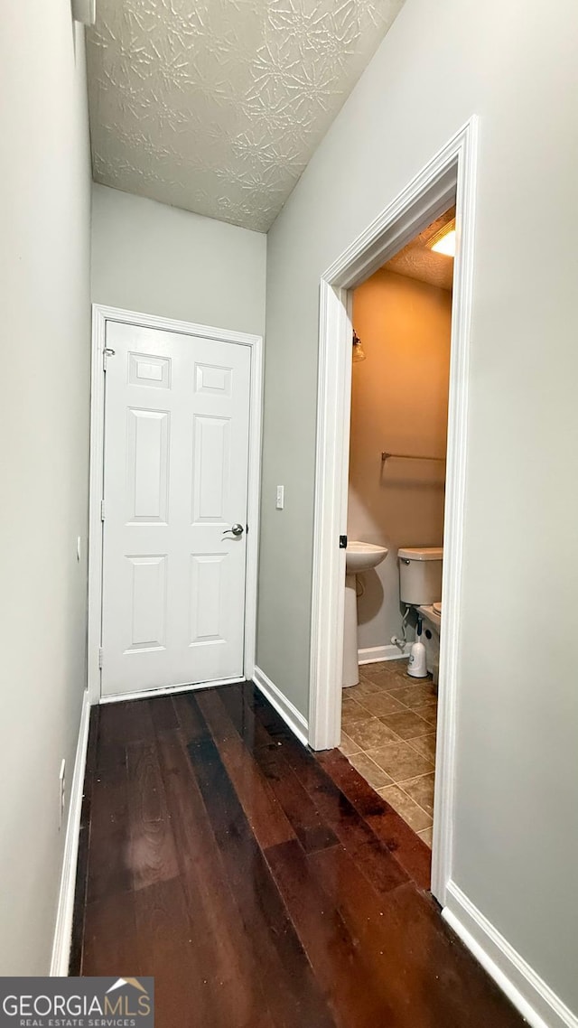 hall with dark hardwood / wood-style flooring and a textured ceiling