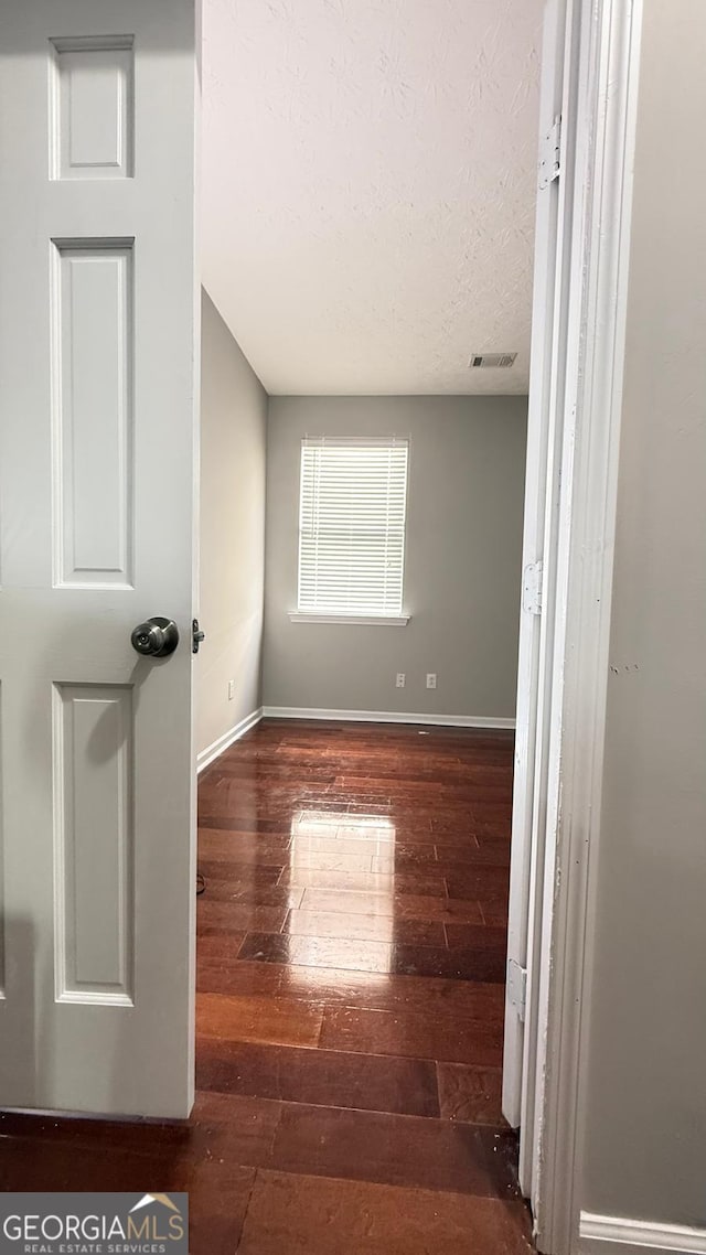 spare room featuring a textured ceiling and dark hardwood / wood-style floors