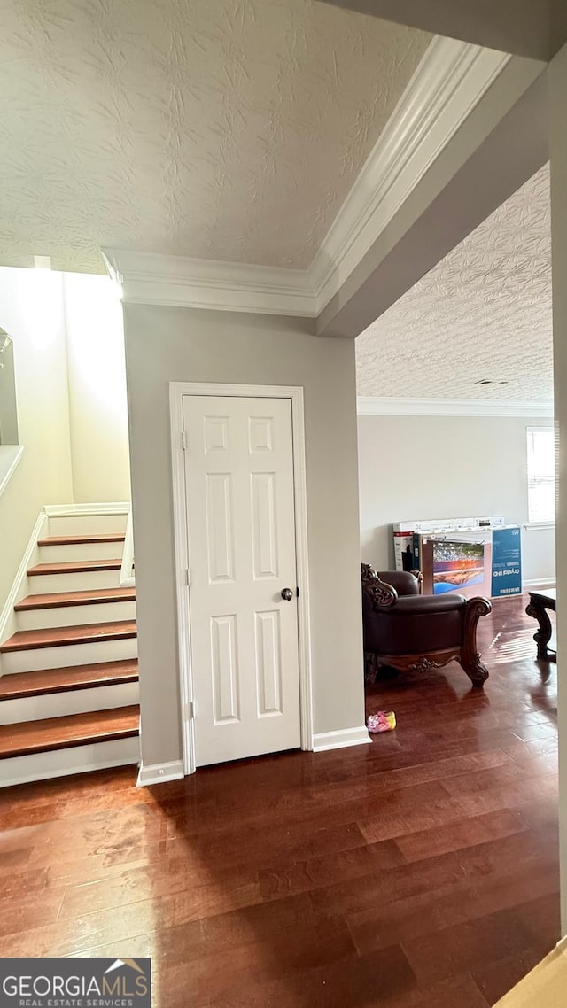 hall with hardwood / wood-style floors, a textured ceiling, and ornamental molding