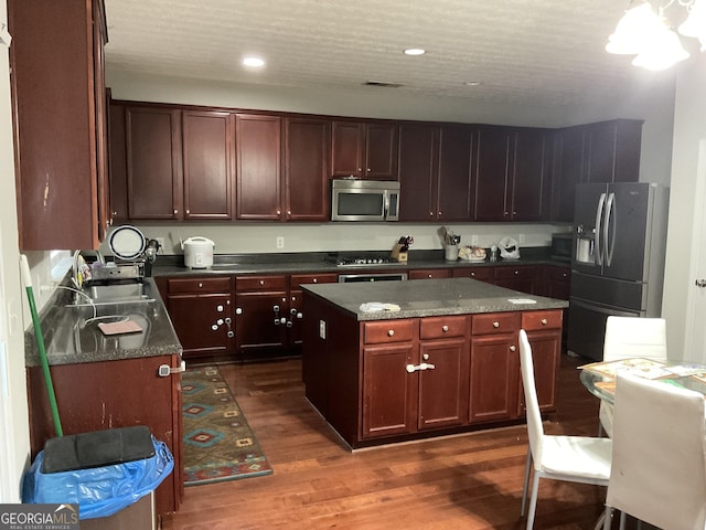 kitchen with dark hardwood / wood-style flooring, a kitchen island, and appliances with stainless steel finishes