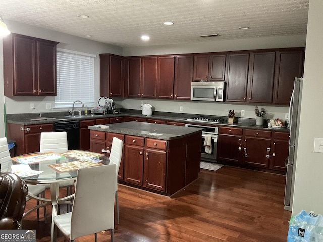 kitchen featuring a textured ceiling, dark hardwood / wood-style floors, a kitchen island, and stainless steel appliances