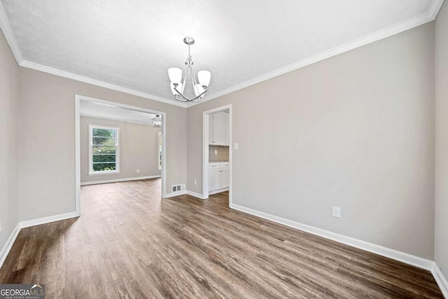 empty room featuring crown molding, dark wood-type flooring, and an inviting chandelier