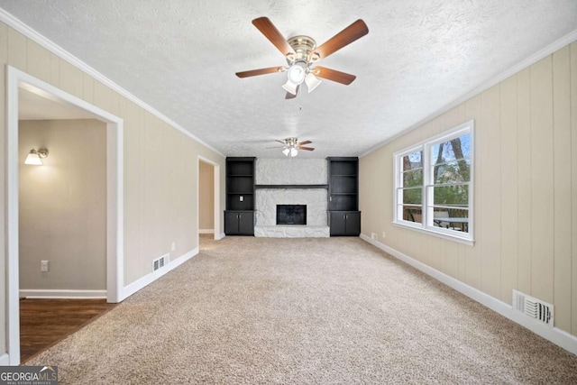 unfurnished living room with a fireplace, a textured ceiling, carpet floors, and ornamental molding