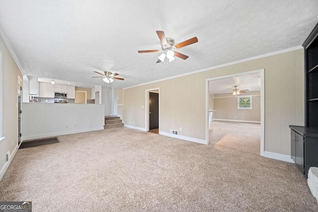 unfurnished living room featuring light colored carpet, ornamental molding, and a textured ceiling