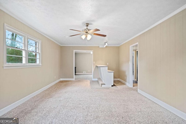 carpeted empty room featuring ceiling fan, crown molding, and a textured ceiling