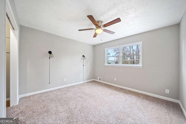 empty room featuring ceiling fan, carpet floors, and a textured ceiling