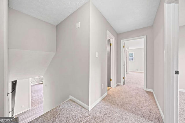 corridor featuring carpet and a textured ceiling