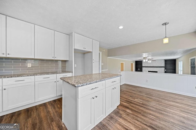 kitchen with decorative light fixtures, white cabinetry, a textured ceiling, and tasteful backsplash