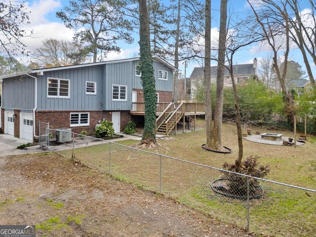 back of house featuring a yard, a garage, a wooden deck, and central air condition unit