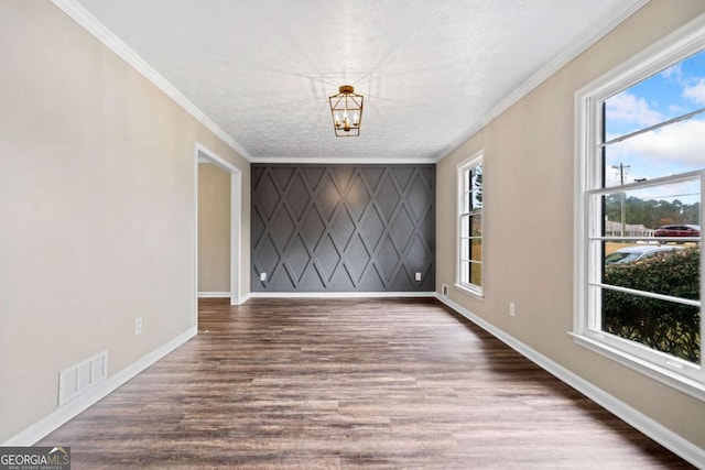 spare room featuring a textured ceiling, crown molding, a notable chandelier, and hardwood / wood-style flooring