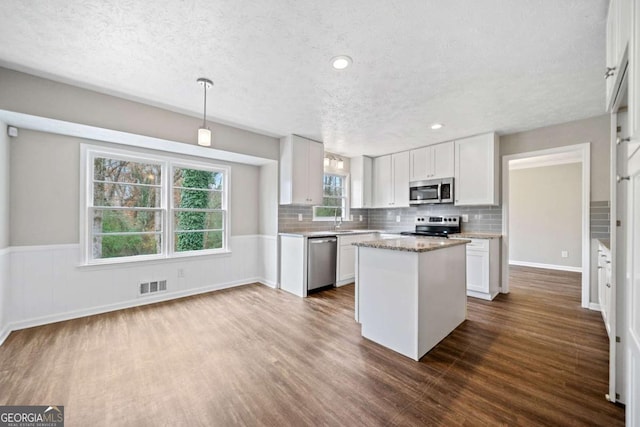 kitchen with pendant lighting, a center island, white cabinets, sink, and stainless steel appliances