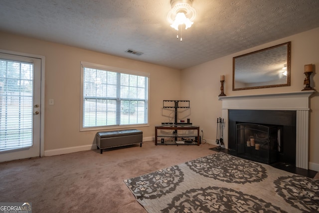 living area featuring a healthy amount of sunlight, carpet floors, and a textured ceiling