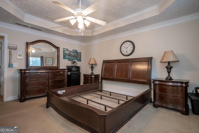 carpeted bedroom featuring ceiling fan, ornamental molding, and a tray ceiling