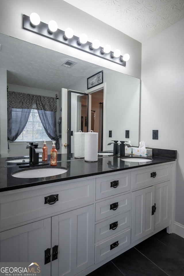 bathroom featuring tile patterned flooring, vanity, and a textured ceiling