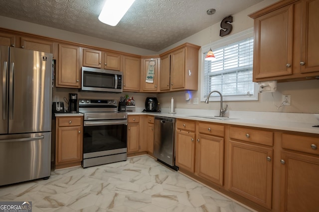 kitchen with pendant lighting, sink, stainless steel appliances, and a textured ceiling