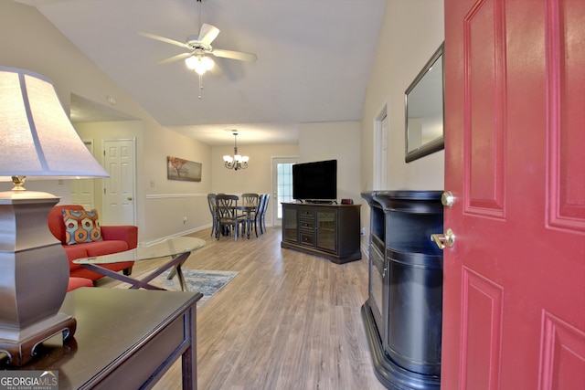 living room featuring wood-type flooring, ceiling fan with notable chandelier, and vaulted ceiling