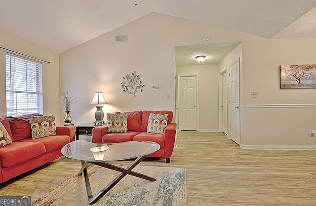 living room featuring vaulted ceiling, a textured ceiling, and light hardwood / wood-style flooring