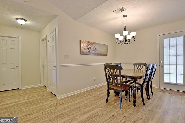 dining space with lofted ceiling, a textured ceiling, light hardwood / wood-style flooring, and a notable chandelier