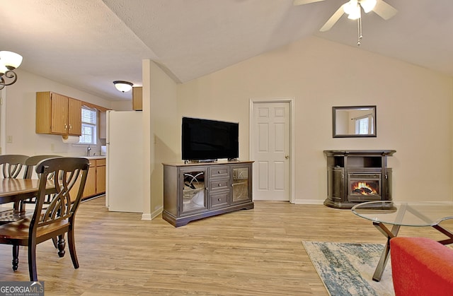 living room with light wood-type flooring, vaulted ceiling, ceiling fan, and sink