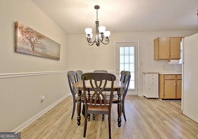 dining space with light hardwood / wood-style flooring and a notable chandelier