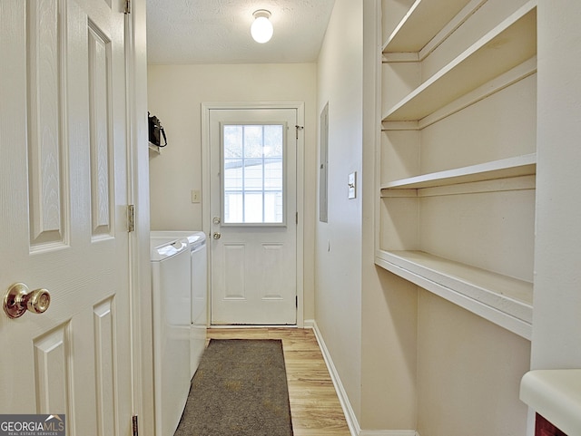 doorway featuring light hardwood / wood-style floors, a textured ceiling, and independent washer and dryer