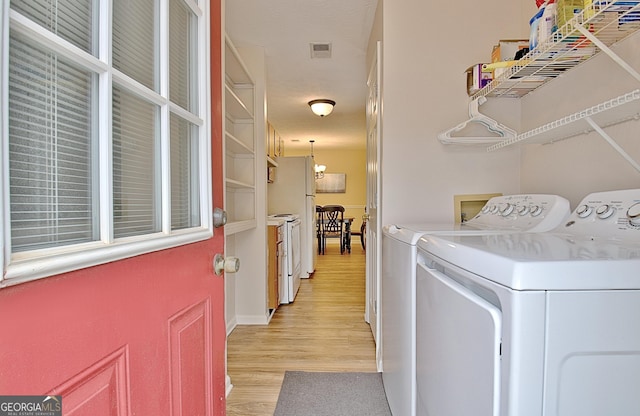 clothes washing area featuring washing machine and dryer and light hardwood / wood-style floors