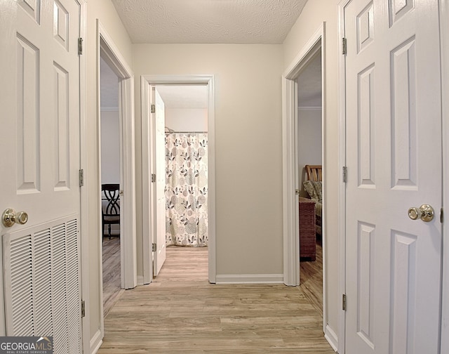 hallway with a textured ceiling and light wood-type flooring