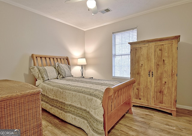 bedroom featuring ceiling fan, crown molding, light hardwood / wood-style floors, and a textured ceiling