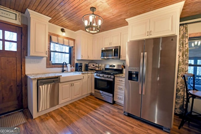 kitchen with light stone countertops, sink, hanging light fixtures, stainless steel appliances, and white cabinets