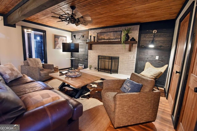 living room featuring a fireplace, beam ceiling, light hardwood / wood-style floors, and wooden ceiling