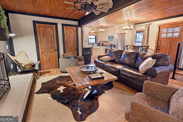 living room featuring plenty of natural light, sink, wood ceiling, and ceiling fan with notable chandelier