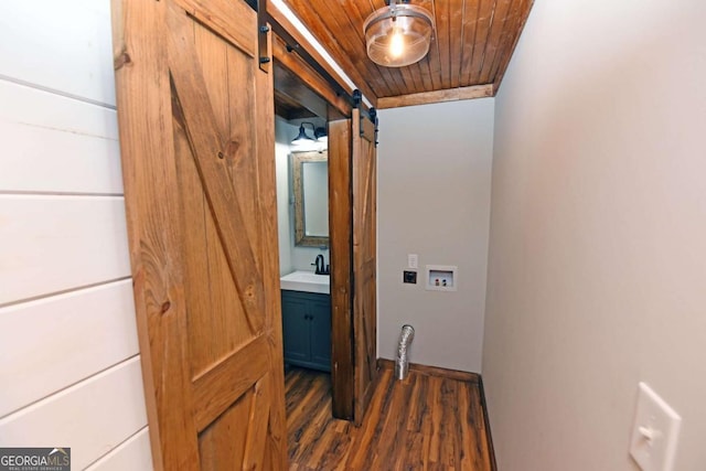 laundry room with sink, wooden ceiling, a barn door, dark hardwood / wood-style floors, and hookup for a washing machine