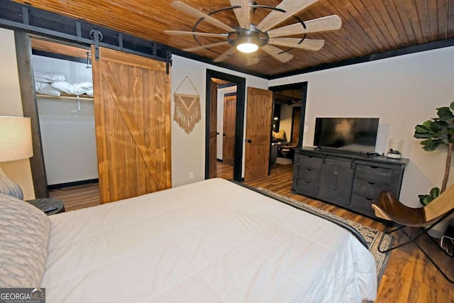 bedroom with a barn door, ceiling fan, wood ceiling, and wood-type flooring