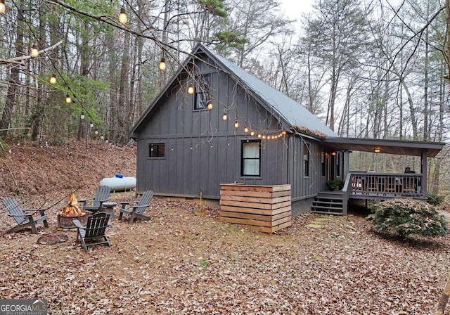 view of side of home with a wooden deck and a fire pit