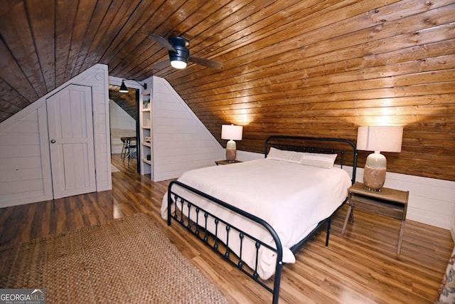 unfurnished bedroom with hardwood / wood-style floors, wood walls, lofted ceiling, wooden ceiling, and ceiling fan