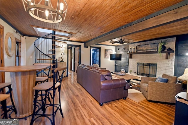 living room with a brick fireplace, ceiling fan with notable chandelier, crown molding, light hardwood / wood-style flooring, and wooden ceiling