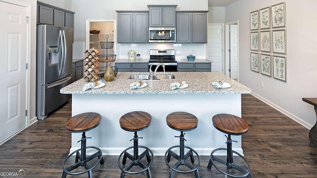 kitchen with stainless steel appliances, a kitchen island with sink, tasteful backsplash, and sink