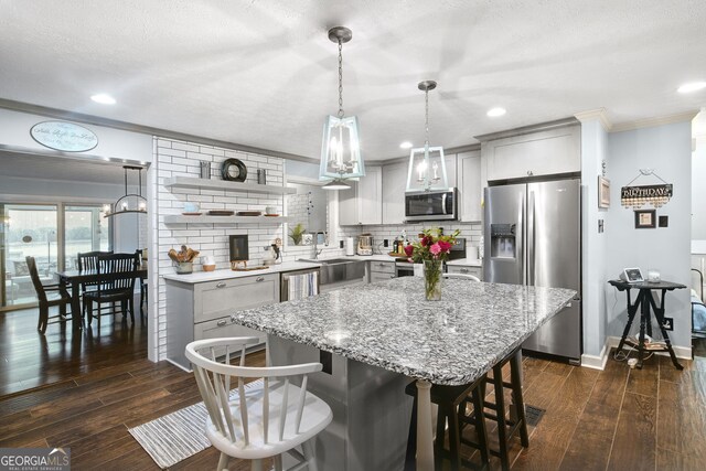 kitchen featuring decorative backsplash, pendant lighting, stainless steel appliances, and dark wood-type flooring