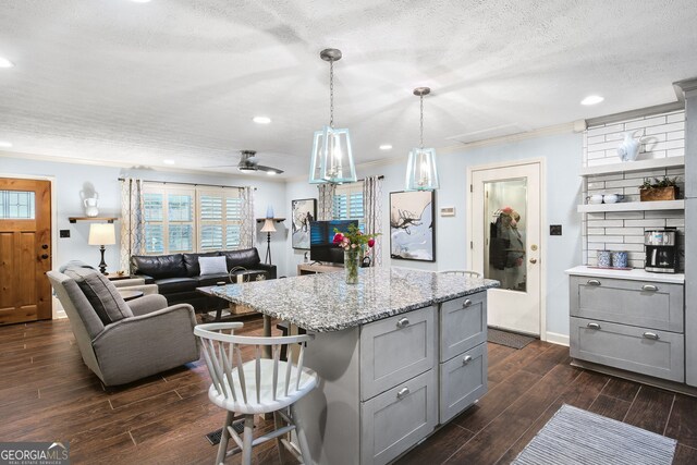 kitchen with a center island, gray cabinets, a textured ceiling, decorative light fixtures, and a breakfast bar area