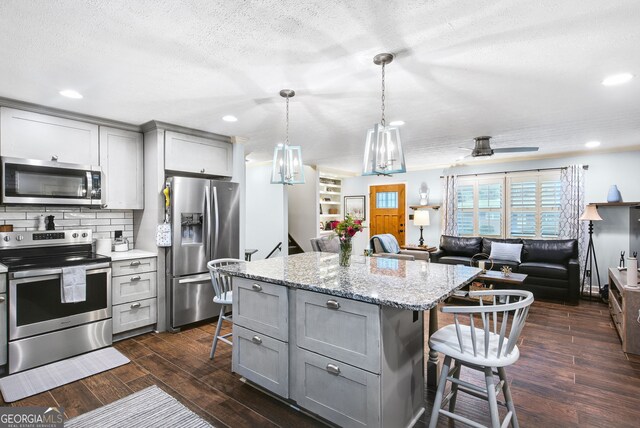 kitchen featuring appliances with stainless steel finishes, gray cabinets, and a breakfast bar area