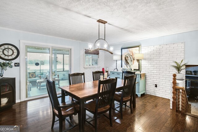 dining area featuring dark hardwood / wood-style flooring, a textured ceiling, crown molding, and brick wall