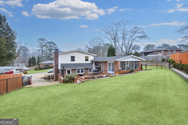 rear view of property with a yard, a wooden deck, and a sunroom