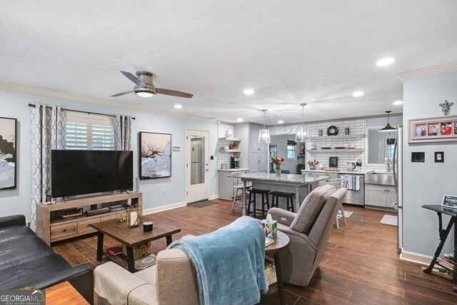 living room with a textured ceiling, dark hardwood / wood-style flooring, ceiling fan, and crown molding